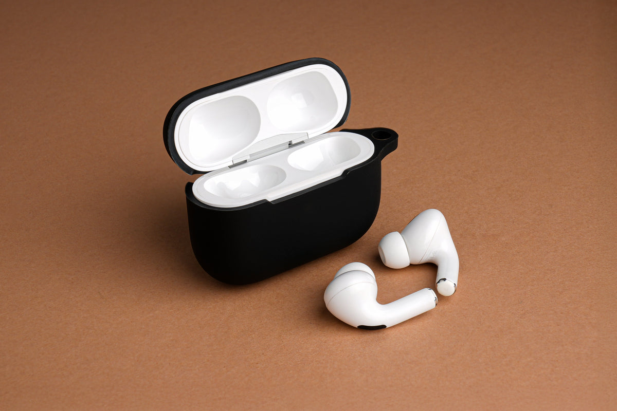 Black Tekne charging case with white earbuds on tan surface