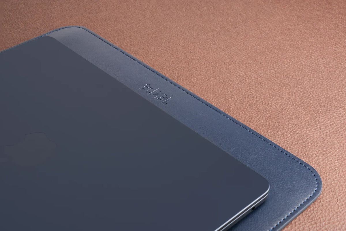 Blue Tekne leather tablet sleeve with embossed logo on tan textured surface