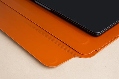 Orange Tekne leather tablet case with black device, stitched edge and embossed lines on beige surface