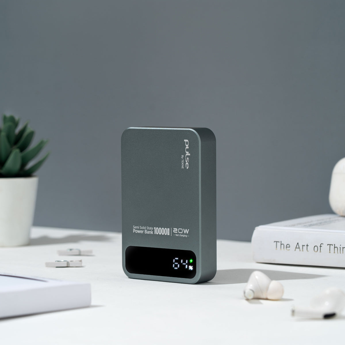 Pulse Tekne 20W power bank with 64% display on desk with earbuds and book
